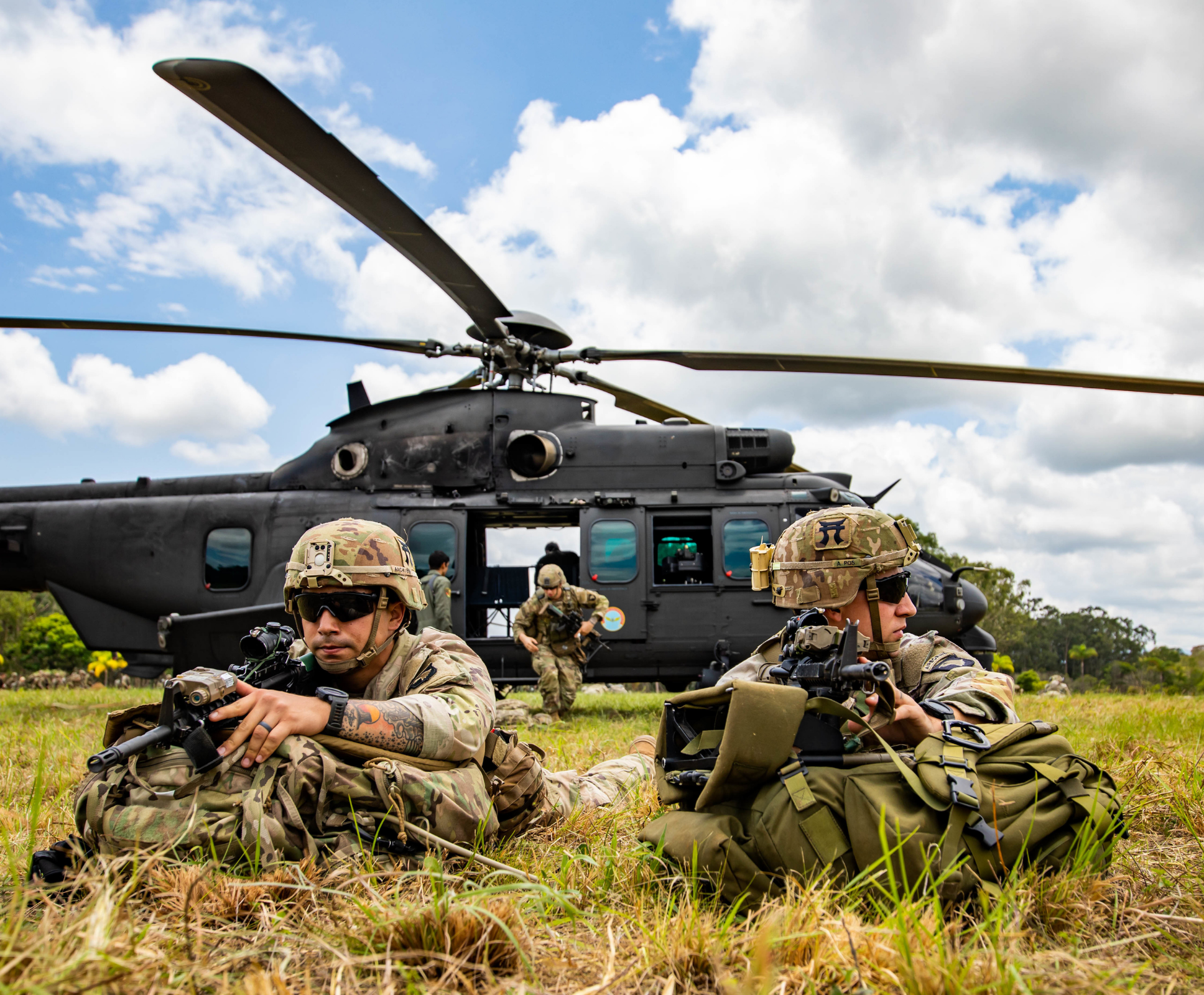 Soldiers posing outside helicopter, weapons in hand